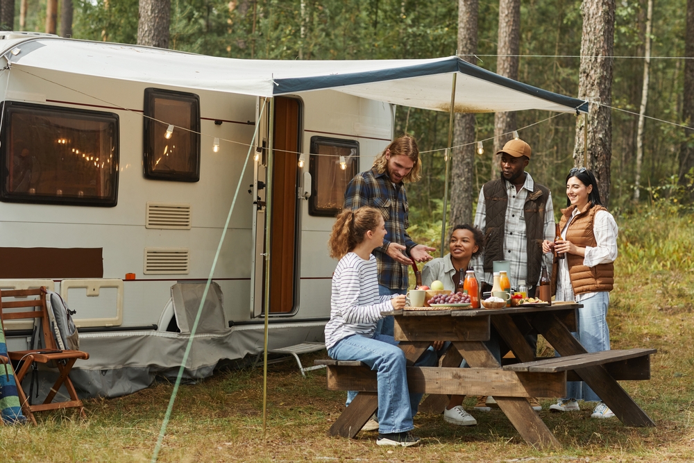 Diverse group of friends sitting at a picnic table in front of RV
