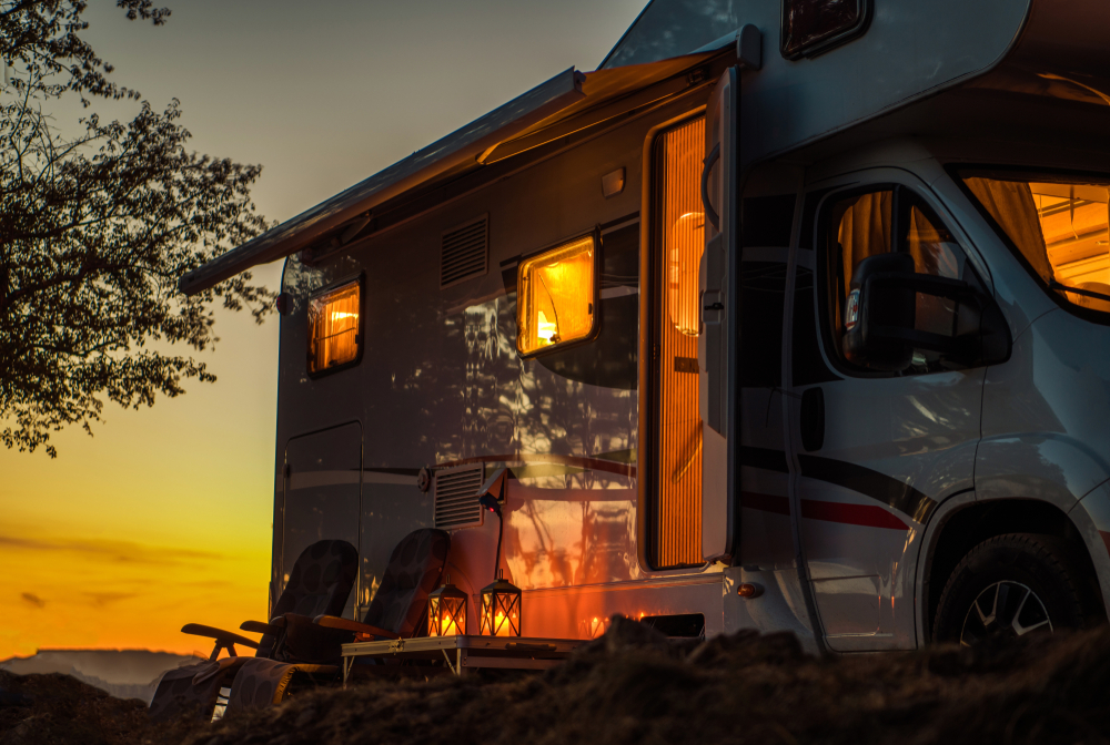 Rv with chairs and lanterns set outside as the sunsets