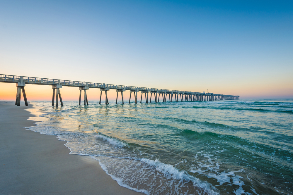 beach with a long pier extending out into the ocean