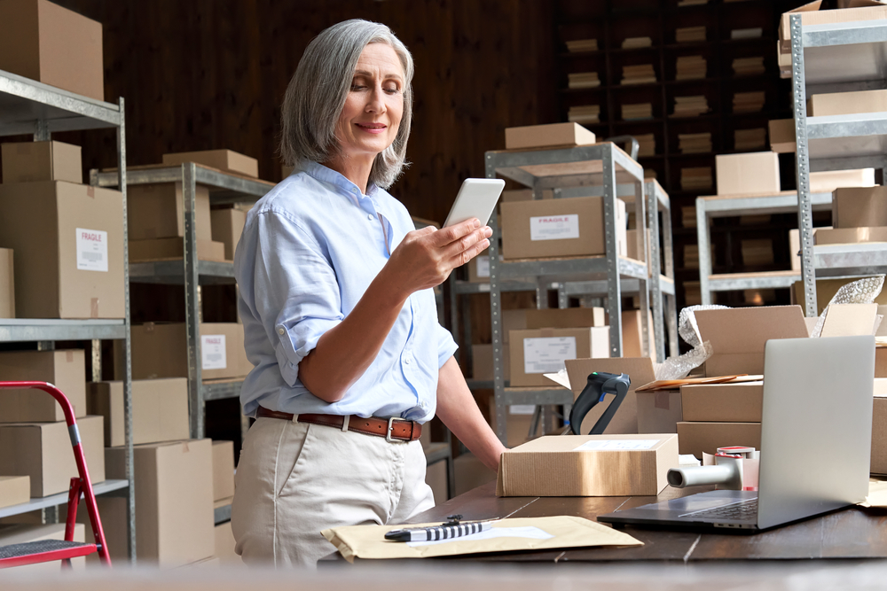 Woman looking at orders and packing boxes to ship out