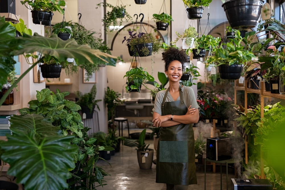 Woman(business owner) standing in front of a few plants