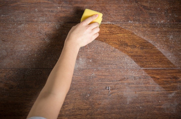 person dusting wood with a sponge duster